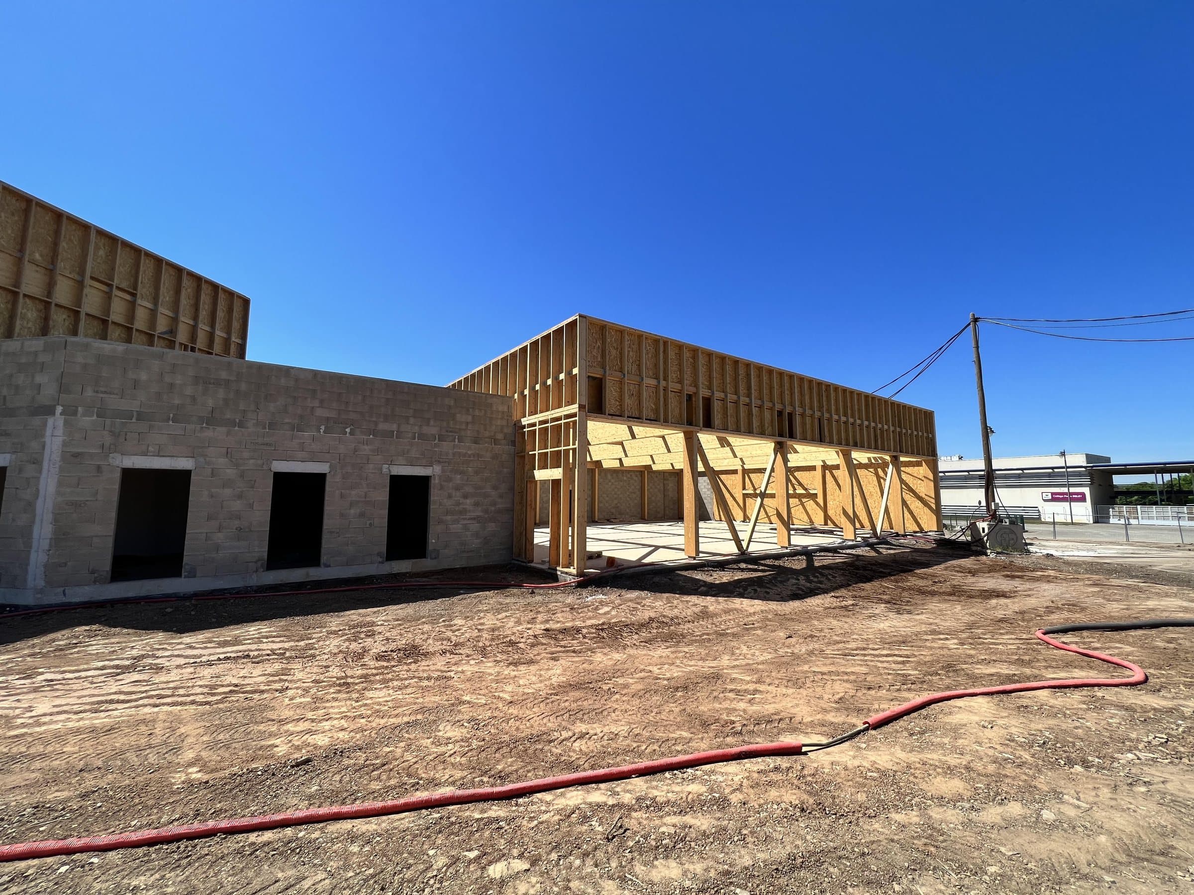 Fachada en obra: muro de piedra y estructura de madera